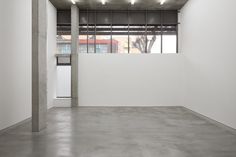 an empty room with white walls and concrete flooring is lit by recessed lights