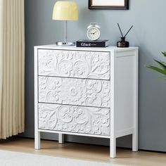 a white chest of drawers with a clock on top