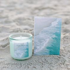 a candle sitting in the sand next to a card