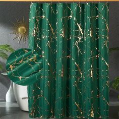 a green shower curtain with gold paint splattered on it and a white toilet in the background