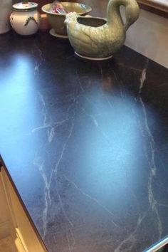 a black counter top in a kitchen with two bowls and a bird figurine on it