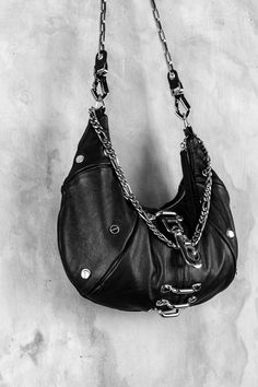 "An ode to the timeless partnership of leather and chains, this leveled up black hobo bag is made from soft, premium genuine black leather and features a top shelf arrangement of silver hardware throughout. currently made to order 2-3 weeks ETA A centered, weighty metal industrial clip takes center stage, accompanied by an array of high contrast chromed out nailed rivets, centered feed through bars, and a draped top chain that doubles as a shoulder strap. Complete with a removable/adjustable lea Black Hobo Bag, Goth Purse, Shelf Arrangement, Fanny Pack Purse, Convertible Crossbody Bag, Hot Bags, Draped Top, Heart Bag, Black Leather Purse