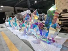 several glass sculptures are lined up on a table in a warehouse with pallets and other materials