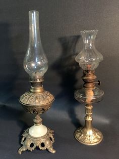 two glass vases sitting next to each other on top of a gray tablecloth