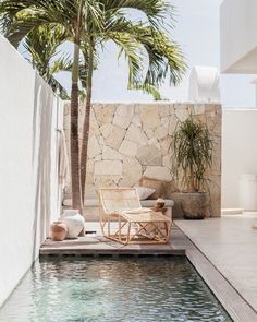 a chair sitting next to a swimming pool near a palm tree in the middle of it