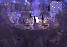 the tables are set with wine bottles and silverware for an elegant wedding reception at night