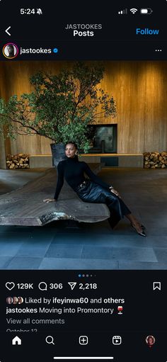 a woman sitting on top of a metal object in front of a tree and building