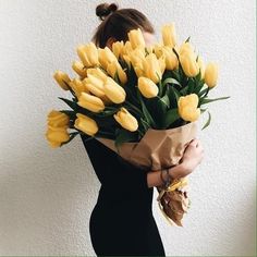 a woman holding a bouquet of yellow tulips