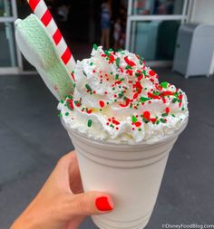 a person holding up a cup with whipped cream and sprinkles