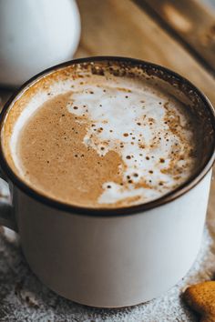 there is a cup of hot chocolate on the table next to some cookies and an egg