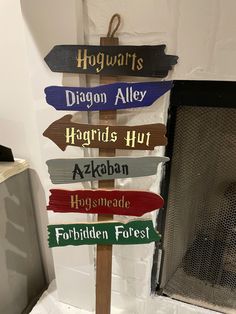 a wooden sign with many different colored signs on it's side in front of a fireplace