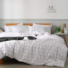 an unmade bed with white sheets and black blankets on the headboard is shown