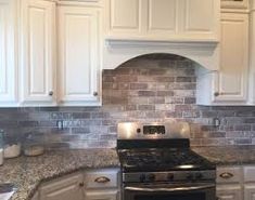 a stove top oven sitting inside of a kitchen next to white cabinets and counter tops