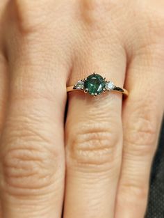 a woman's hand with an emerald and diamond ring