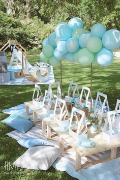 an outdoor party with balloons and decorations on the grass in front of a picnic table