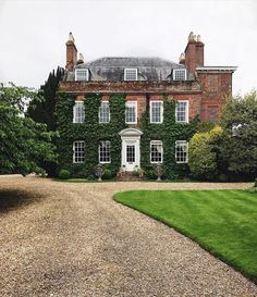 a large brick building with ivy growing on it's sides and two driveways leading to the front door