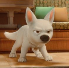 a white dog standing on top of a tile floor next to a couch and table