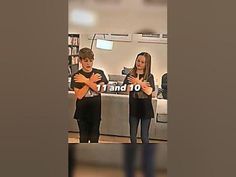 two people standing in front of a book shelf holding their arms crossed and looking at each other