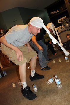 a man in grey shirt and khaki shorts playing video game with plastic water bottles