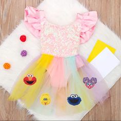 a dress with sesame characters on it and some other items next to it, sitting on top of a fur rug