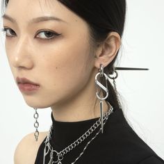 a woman with black hair wearing silver chains and dangling earring earrings on her neck