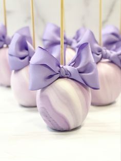 there are several candy apples with purple bows on them and gold sticks sticking out of them