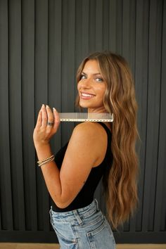 a woman holding a comb in front of her face and looking up at the camera