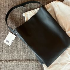 Mint Condition, Never Used. Folded Shopper Black 100 Percent Leather Cos Tote Bag With Adjustable Straps. Ideal Size For Laptop. Has A Clean Folded Modern Shape And A Secure Magnetic Closure And Polished Silver Hardware. Square Leather Bucket Bag With Dust Bag, Designer Tote Hobo Bag For Office, Designer Hobo Tote Bag For Office, Square Leather Hobo Bag With Dust Bag, Designer Square Hobo Bag For Everyday, Sleek Smooth Grain Tote Shoulder Bag, Structured Black Shopping Bag, High-capacity Black Tote Bag, Cos Black Leather Bag