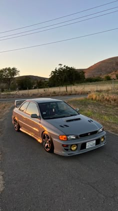 the car is parked on the side of the road in front of some power lines