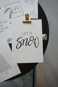 some white paper with black writing on it and a clipboard that says let it snow