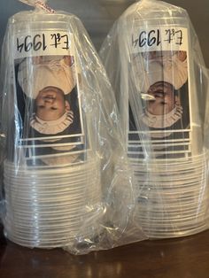 two plastic cups with pictures of babies on them are wrapped in plastic and sit on a table