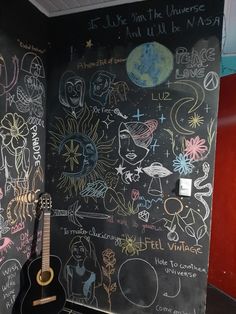 a guitar is sitting in front of a chalkboard with writing on it and an image of the moon