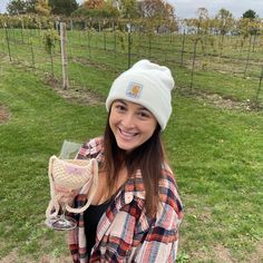 a woman holding a wine glass in her hand and wearing a white beanie hat