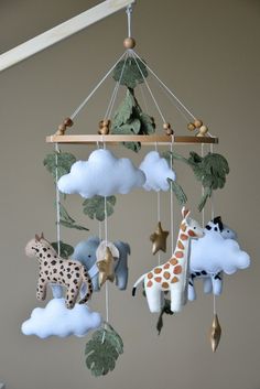 a baby mobile with stuffed animals hanging from it's sides and clouds in the background