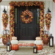 a front porch decorated for fall with pumpkins and lanterns