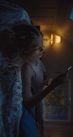 a girl is standing in the dark with her cell phone