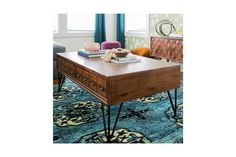 a coffee table with some books on it in front of a blue and green rug