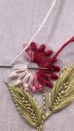 a close up of a piece of cloth with some thread on it and two flowers in the middle