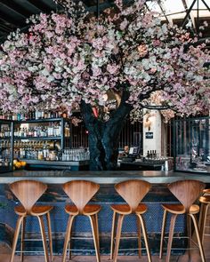 the bar is decorated with pink flowers and barstools, along with wooden stools