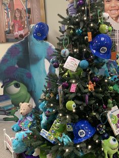 a christmas tree decorated with monsters and other toys in front of a child's portrait