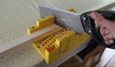 a person holding a large knife over a piece of wood with legos on it