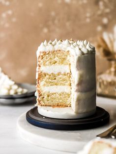 a slice of cake with white frosting sits on a plate next to the rest of the cake