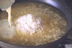 a ladle pouring gravy into a pot filled with rice and other ingredients