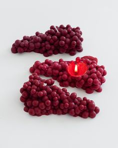 a red candle sitting on top of a white table next to some grapes in the shape of numbers