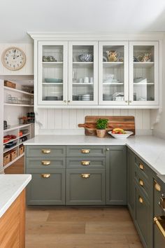 a kitchen filled with lots of cabinets and counter top space next to a clock on the wall