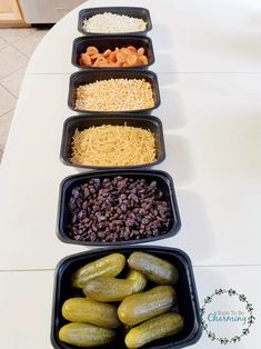 four trays filled with different types of food on top of a white tablecloth