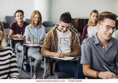 group of students sitting at desks in classroom with one student taking notes and smiling