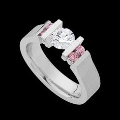 a white gold ring with pink and white diamonds on the sides, set against a black background