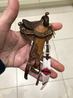 a hand holding a small brown and white saddle