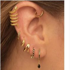 a woman wearing gold ear cuffs with black stones